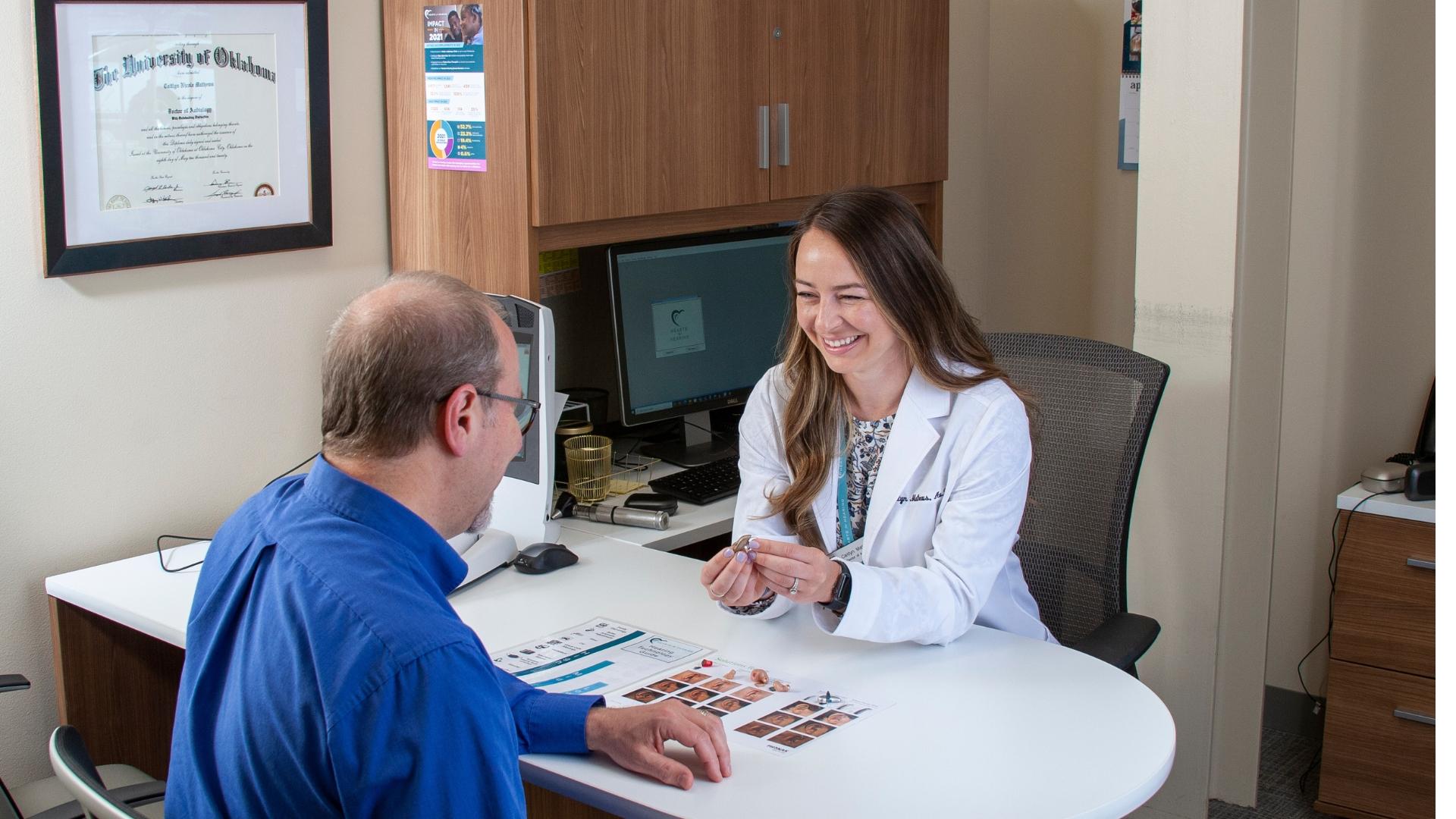 audiologist discussing options with male adult patient for custom hearing aid devices