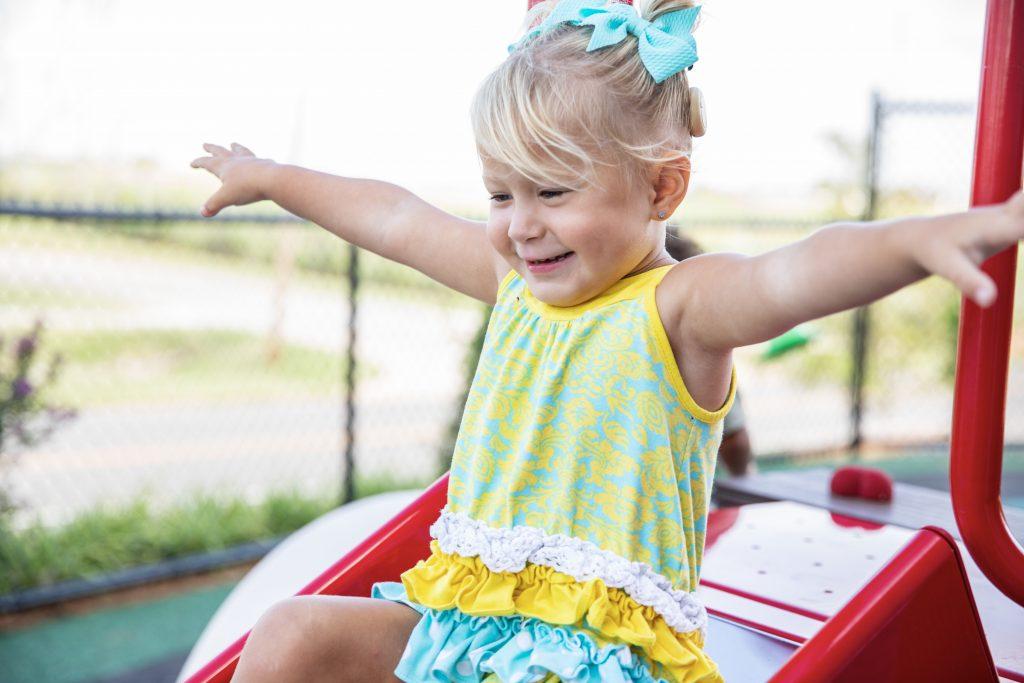 young girl smiling and playing on new playground