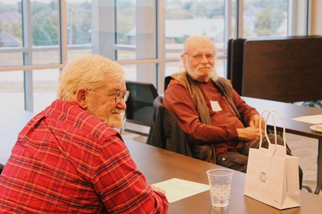 two older adult gentlemen sitting and smiling