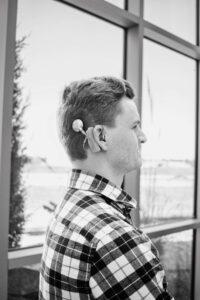 A black and white photo of Peter Hardt. He is standing with his side to the camera, his cochlear implant is visible