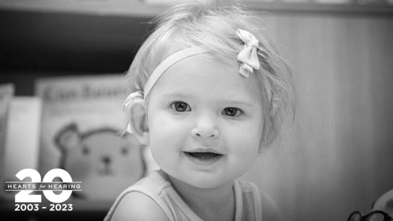 a young girl smiling with a bow in her hair