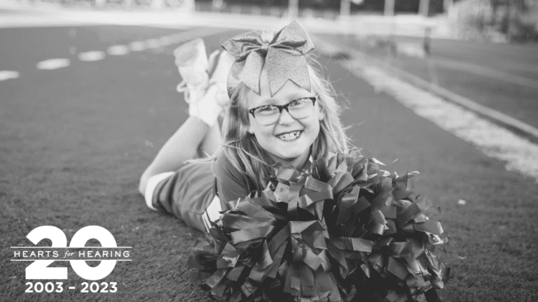Photo of Josie sitting on a football field in a cheerleading uniform