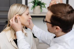 Audiologist putting hearing aids on patient.