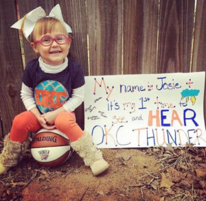 Three-year-old Josie with a sign reading "My name is Josie and this is my first time to see and HEAR the OKC THUNDER!"