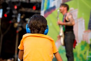 A kid at a concert with hearing protection.