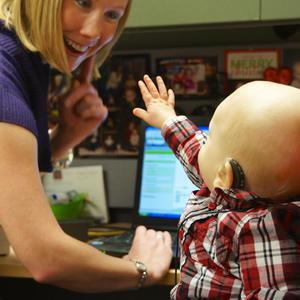 young boy with hearing aid technology reaching for friendly audio care technician