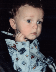 a baby in a blue shirt wearing hearing technology