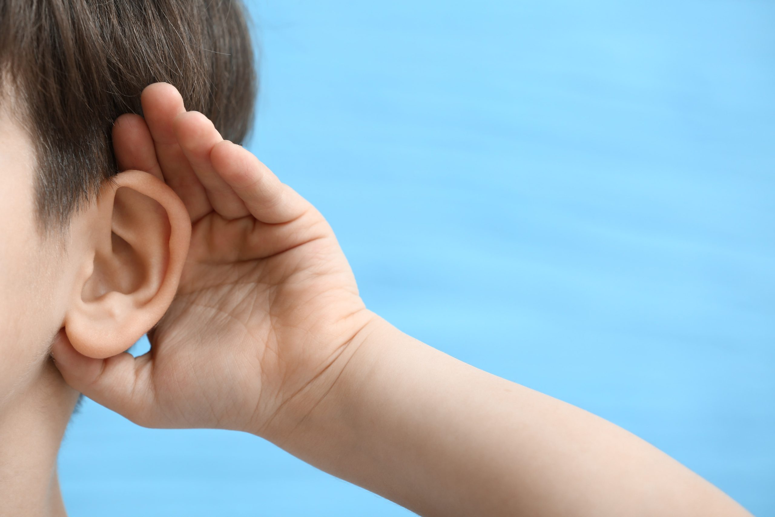 Child with their hand to their ear.
