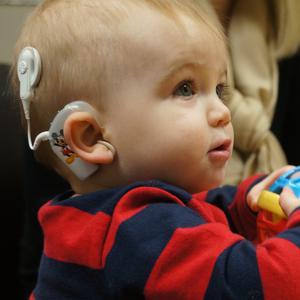 young boy playing while wearing cochlear implant technology helping him to hear