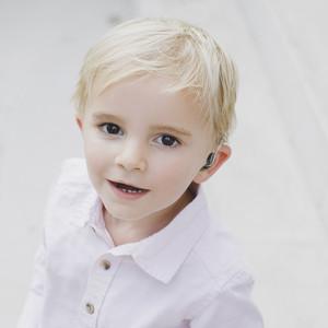 young boy smiling with hearing aid technology