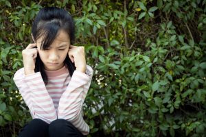 Teen girl with fingers in her ears.